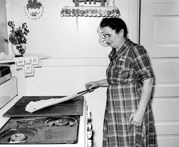 Mrs. Roy J. Nelson, 145 Marquette Street, is shown using a "floyve" stick to turn the lefsa while it bakes. She and her two sisters gathered at one of their homes to carry on a 30 year, Christmas time tradition of making a year's supply of lefsa.