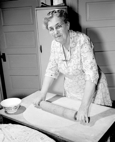 Three daughters of Mrs. John G. Peterson gathered at one of their homes every year to carry on a 30 year, Christmas time, tradition of baking lefsa, a Norwegian flatbread. Mrs. Robert Nelson, 2829 Milwaukee Street, rolls the flattened, round cake called "aevna" until the sheet is more than two feet in diameter and paper thin.