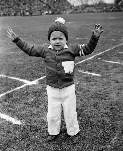 Billy Haase, two-and-a-half-year-old nephew of University of Wisconsin cheerleader Dick Onstead, is decked out in a "W" sweater at the football game between Wisconsin and Minnesota at Camp Randall Stadium.