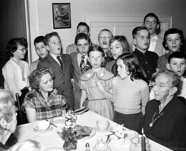 Members of the Sherman Avenue Methodist Church junior choir sing Christmas songs for Oakwood Lutheran Home residents. Shown seated at a table are Almira and Cora Ogden.