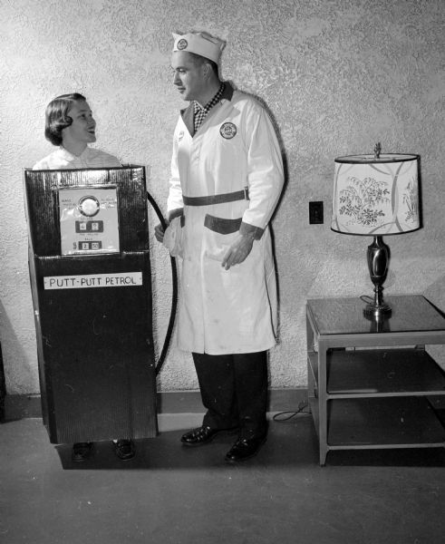 Alfred and Nancy Ellrodt dress as a gasoline pump and station attendant at the "Mardi Gras" dancing party of the Chameleon Club at the Nakoma Country Club. They won the prize for the most original costume.