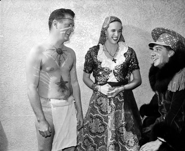Dr. M.W. Penrose, Julia Dolphin, and John Lenahan admire each other's costumes at the "Mardi Gras" dancing party of the Chameleon Club at the Nakoma Country Club.