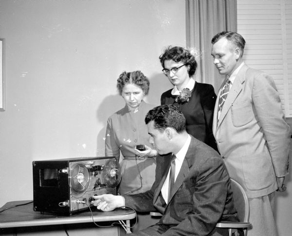 Lee Dolnick of the Wisconsin Anti-Tuberculosis Association plays a tape recording explaining the upcoming Dane County health survey project. Looking on are Mrs. Monroe Tubbs, Cross Plains, health chairman of the Dane County homemakers; Jacqueline Morris, Madison, Dane County home demonstration agent; and Anfin Christenson, Rockdale, a member of the Dane County board.