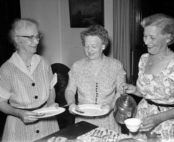United Church Women board members attend a breakfast to honor their president, Mildred Campbell, who will be moving from Madison. Gladys Kneebone (left), Clara Erickson, and Mrs. Ralph Thomas serve themselves at the buffet table.