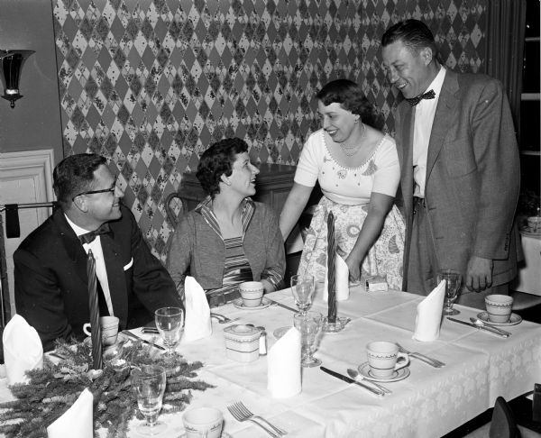 Guests attend a dinner and dance sponsored by the auxiliary of the Dane County Dental Society. Seated at the table are Dr. Harris and Ruth Keel. Stopping to chat with them are Dr. Charles and Marjorie Thielke.
