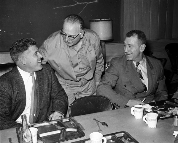 Host Joe Betlach standing between head football Milt Bruhn (left) and athletic director Ivan Williamson at a University of Wisconsin athletic department dinner.
