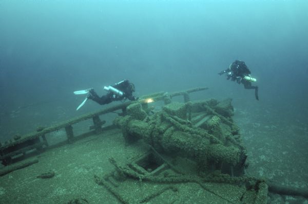 Underwater overhead view of the collision damage and the deck of the schooner <i>Home</i>. Two underwater archeologists are surveying the site.