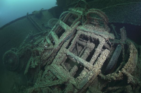 Underwater view of two automobile frames that were part of the final cargo of the steamer <i>Lakeland</i> A section of the ship's deck is in the background.