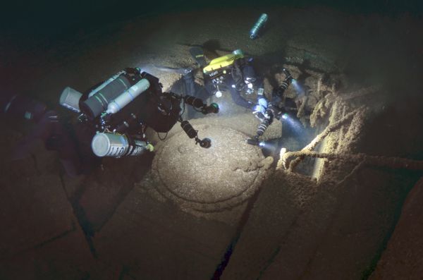 Underwater view of two archeologists surveying a portion of the <i>Lakeland.</i> The divers are using cameras, with three or four strobes attached by an arm system, to light and photograph the ship.