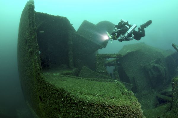 Underwater view of an archeologist examining the bow of the <i>Milwaukee</i>.