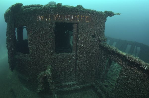 Underwater view of the door to the chartroom of the <i>Milwaukee</i>. Despite the growth of algae and mussels on the entire structure, the word <i>Milwaukee</i> can be seen above the door in yellow letters.