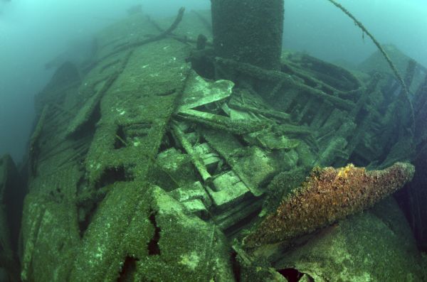 Underwater view of a portion of the wreck of the <i>Milwaukee</i>. In the center a portion of the last cargo, a pile of sinks stacked together, are resting among the ruins of the ship.