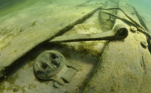 Underwater view of one of the deadeyes, in the middle of the ship along the port side, used on the scow schooner <i>Success</i>. The ship and rigging are partially buried in sand.