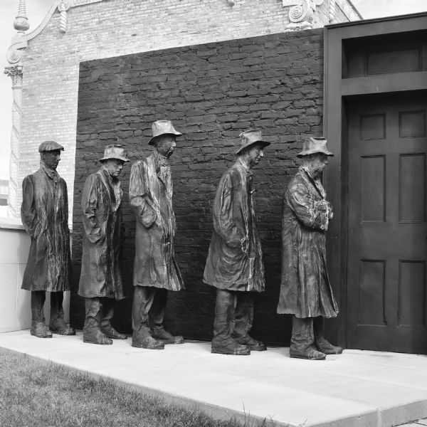 The bronze and plaster sculpture by George Segal depiciting five men waiting in a bread line at a door. The sculpture is on the rooftop garden of the Madison Museum of Contemporary Art.  