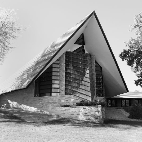View across lawn towards the sharp angular roof and protruding triangular shaped windows of the First Unitarian Meeting House designed by Frank Lloyd Wright.