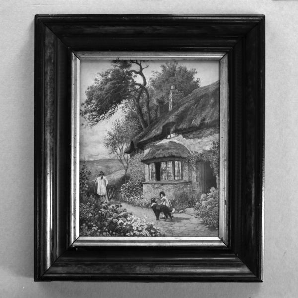 View of a painting hanging on a wall in a frame. The painting is of an English cottage with a girl and a dog and a waiting parent.