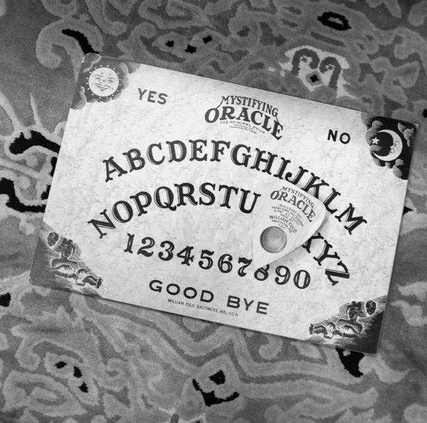 View of a Ouija board lying on an ornately detailed rug.
