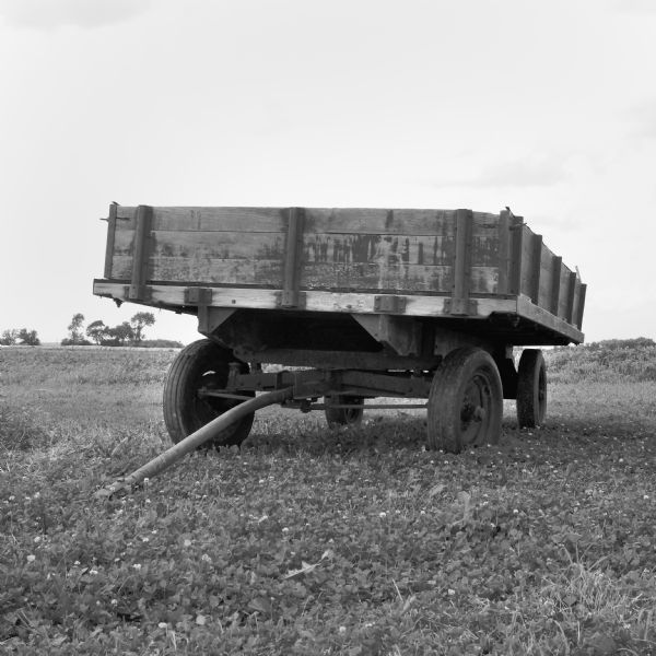 An old, worn farm wagon sitting in a field.