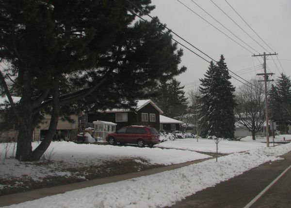 View down road toward a house at 4718 Odana Road, the former location of the Piper Brothers farm. An automobile is parked in the driveway, and snow is on the ground.