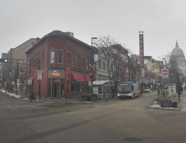 A view at the corner of the 200 block of State Street and West Johnson Street, including Noodles & Company, the Orpheum Theatre and the Wisconsin State Capitol.
