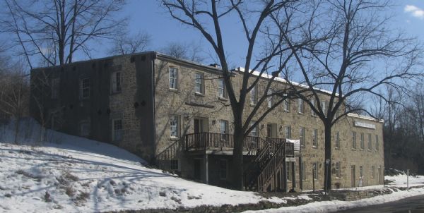 Exterior view, with snow on the ground, of the Walker House on 1 Water Street. The stone house functions as a guest house/hotel.