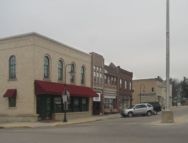 A view of downtown Mazomanie from the corner of Broadhead and Hudson Streets, including brick buildings, streetlamps, and parked cars.