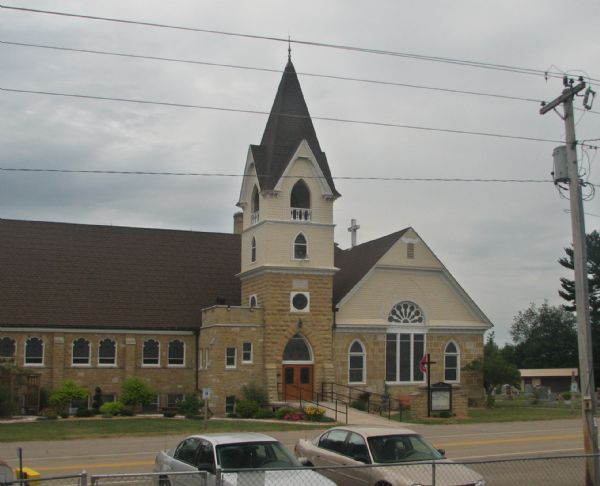 Elevated view of a church with arched windows and a cemetery at the side of the building. 