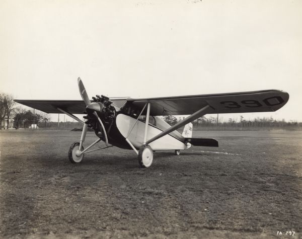 Three-quarter front view from left of a Fairchild Model 71 sitting on a runway. The tail identifier reads: "390." 