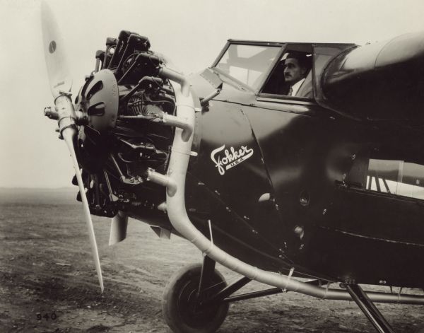 Side view of front of a Fokker Super Universal with pilot sitting inside. The improved cockpit enclosure allows for better visibility for the pilot.