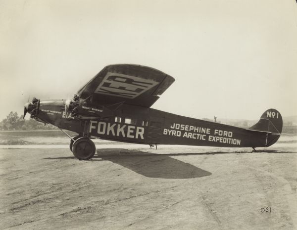 Left side view of a Fokker F-VIIA Trimotor sitting on the runway. This airplane was bought by Edsel Ford in 1926, and he named it after his daughter, Josephine Ford. It was donated to pilot Richard Byrd's arctic expedition. Byrd was the first pilot to fly across the North Pole. On May 9, 1926, Byrd set out with co-pilot Floyd Bennett, and despite an oil leak, supposedly managed to make the flight from Spitsbergen to the North Pole and back in under 16 hours. Painted on the side of the airplane is: "Wright 'Whirlwind' Engines," "BA," "Fokker," "Josephine Ford," "Byrd Arctic Expedition." The tail identifier reads: "No. 1."