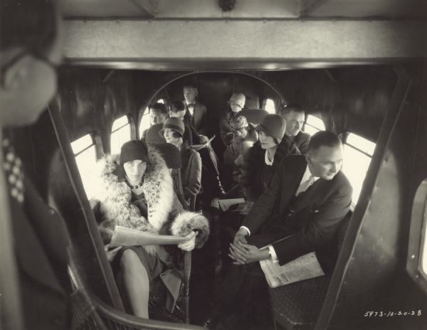 Interior view from front of a Ford all-metal trimotor monoplane with ten passengers sitting inside.