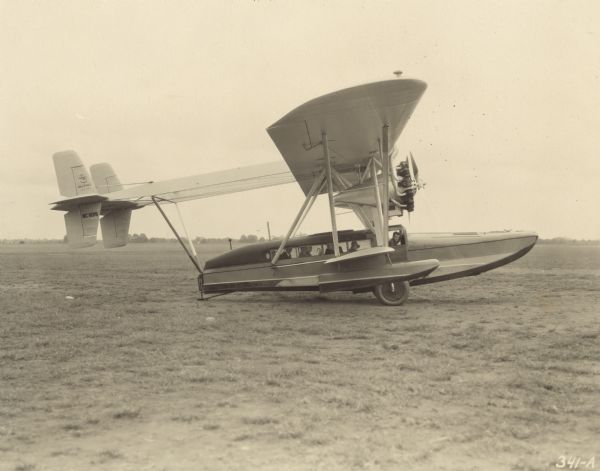 Right side view of a Sikorsky S-38A sitting on a runway. The tail identifier reads: "NC8019." Five passengers and one crew member can be seen through the windows sitting inside the plane. The amphibious airplane was equipped with two 400 hp Pratt & Whitney Wasp engines and could seat 8 passengers and 2 crew members.