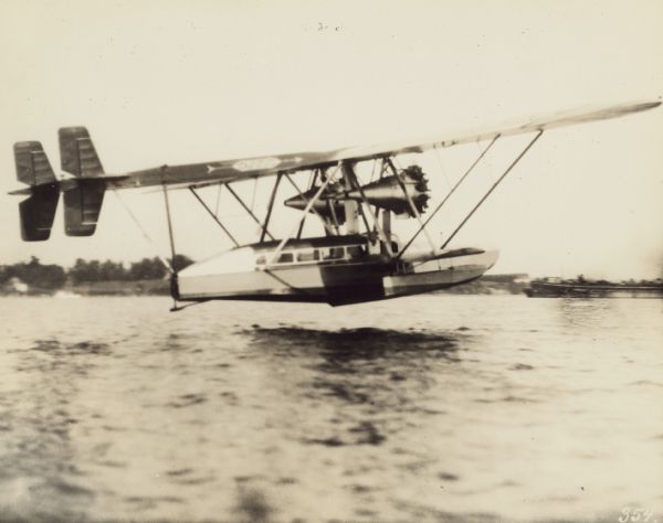 Right side view of a Sikorsky S-38, an amphibious airplane equipped with two Pratt & Whitney Wasp engines, in flight flying low above a body of water,