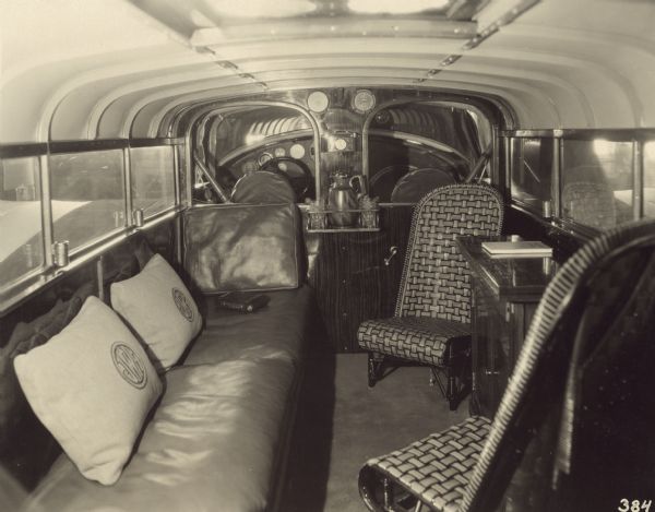 An interior view of Jock H. Whitney’s luxurious flying yacht, NC8005, c/n 14-2, featuring a spring couch with leather cushions, special high-back chairs, cabinet with drawer and folding table top, and flight instruments for the passengers’ information. The cockpit can be seen through two interior windows.