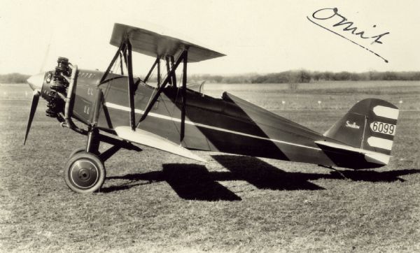 Left side view of a Swallow G-29 sitting on a runway. The ail identifier reads: "6099." This monoplane was powered by a 225 hp Wright J-5 Whirlwind engine. 