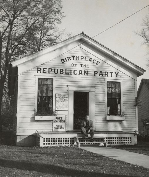 View across lawn towards Sid Boyum sitting on the steps of the meeting house where the Republican Party held its first meeting in Ripon.