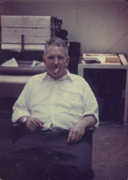 Sid Boyum siting in an office at Gisholt with a cigar in his mouth.