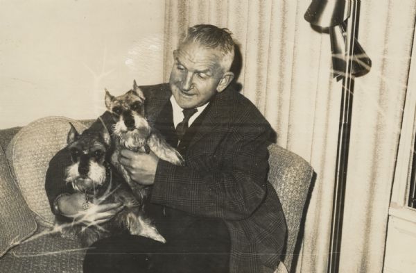 Sid Boyum sitting on a couch with two terriers in his lap.