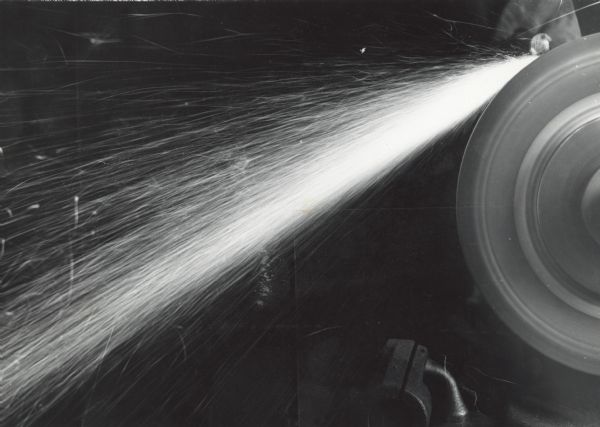 Close-up of an industrial grinding wheel throwing sparks at the Gisholt Machine Company.