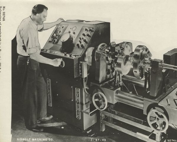 A male employee standing at a machine. The caption along the left reads: "No. 9274A/Balancing a crankshaft in a Dynetric 3U Balancer." Gisholt Machine Company is printed in the lower left corner; 1-27-43 is in the bottom center; 9274A  is bottom right.