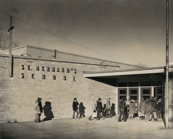 Children wearing coats and jackets walking into the St. Bernard's School entrance. (The building is located on Atwood Avenue down the street from St. Bernard's church.) 
