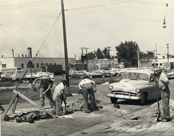 Workers doing road work near the Red Dot factory, in the background, on East Washington Avenue.