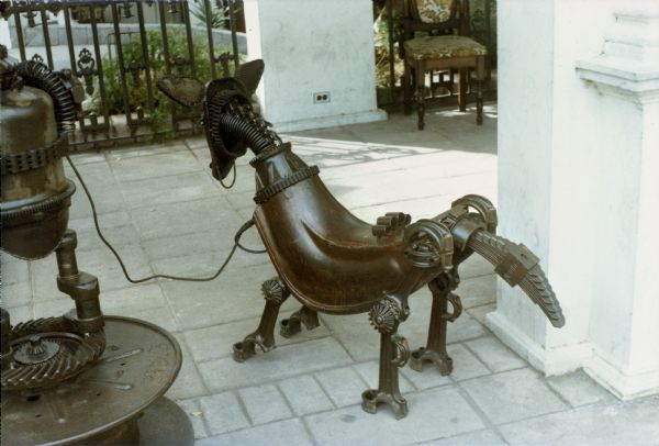 Side view of an animal sculpture on a patio or porch. The creature was built by Dr. Evermor from scrap metal which he collected and designed and assembled. Dr. Evermor, or Tom Every, was a friend of Sid's.