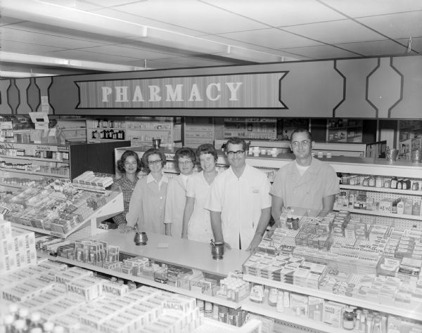 Elevated view of a group portrait of the employees posing behind the counter of the Cooperative Pharmacy of Madison. 