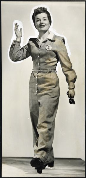 Illustration art of a full-length view of a female factory worker, waving her right hand as she steps toward the viewer. She is wearing belted coveralls over a white shirt. Her photographic name badge is on her left breast-pocket. Her hair is wrapped in a scarf and she is carrying safety goggles.