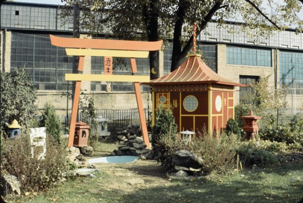 Japanese Tea Pavilion, a large arch, an Oriental Ground Lantern and other sculptures in Sid's backyard. Madison-Kipp Corporation is in the background.