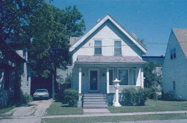 View of 237 Waubesa Street. The "Tall White Lantern" sculpture is standing near the front steps of the porch. 