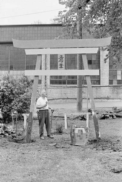 Sid looking up at the torii gate in his backyard. Madison-Kipp Corporation is in the background behind a chain-link fence.