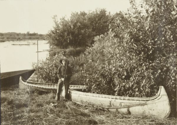 One of the boys (probably Carl) posing next to two canoes at an Indian village below Pansy.