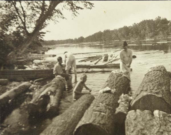 The travelers are washing their clothes in the St. Croix River. There are a number of logs at the river's edge.